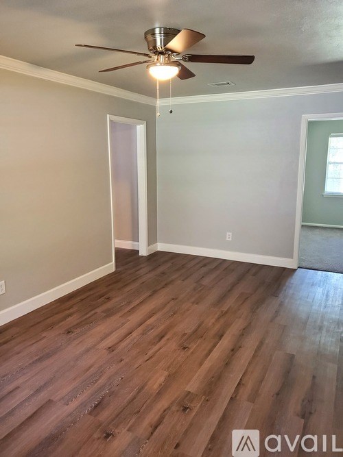 A room with a ceiling fan and wood flooring.