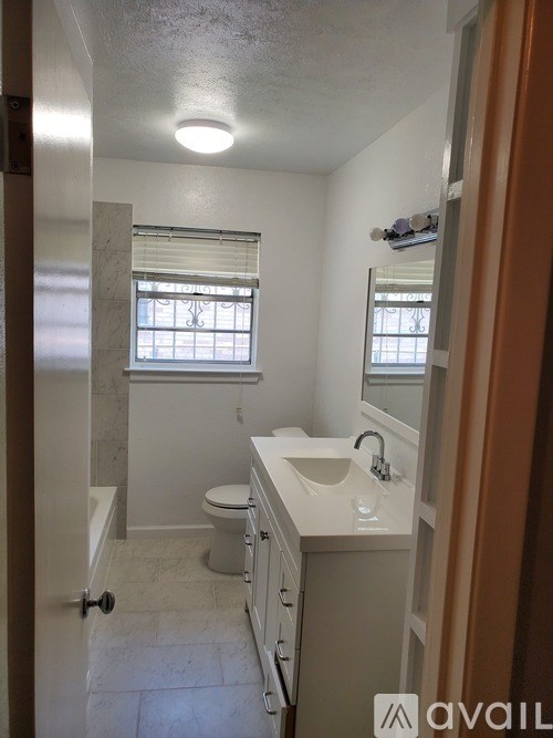 A bathroom with a toilet, sink, and mirror.