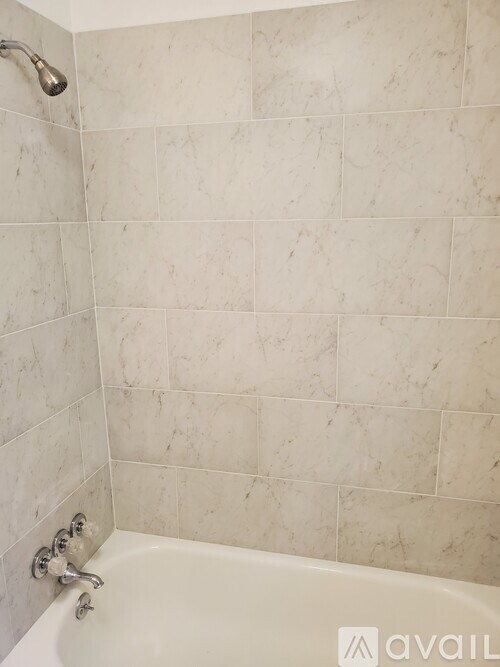 A white bathtub with a shower head and faucet.