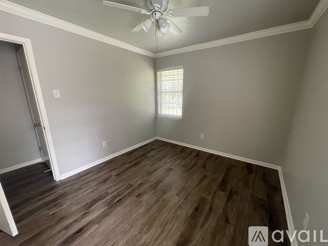 A room with a ceiling fan and a window with blinds.