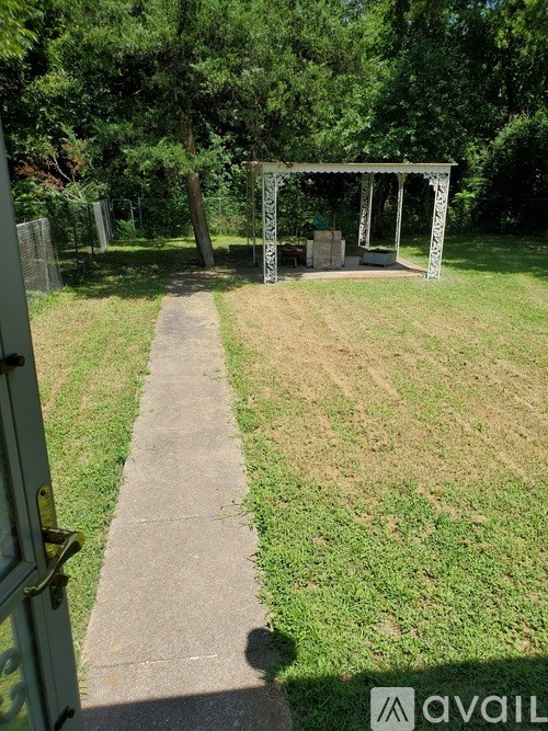 A garden with a concrete pathway leading to a white pergola.