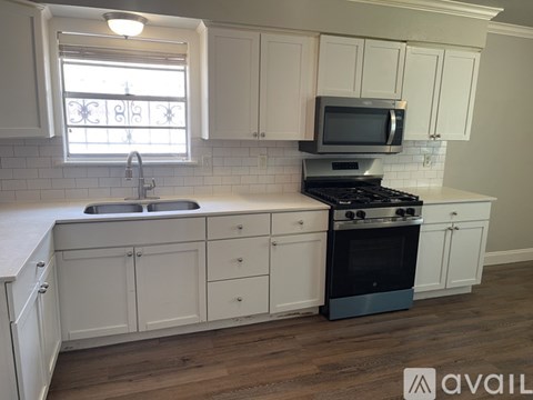 A kitchen with white cabinets and a black stove top oven.
