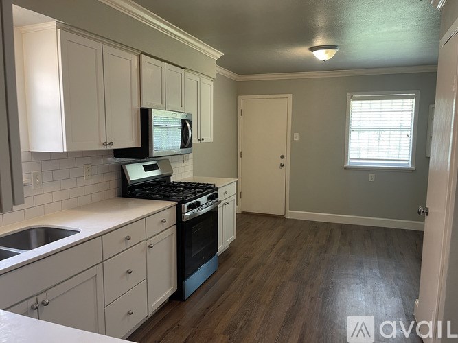 A kitchen with white cabinets and a black stove top oven.