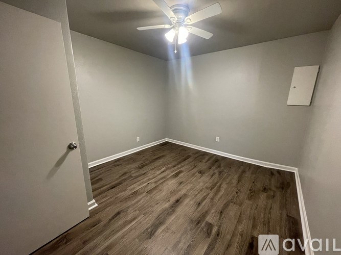 A room with a ceiling fan and wooden flooring.