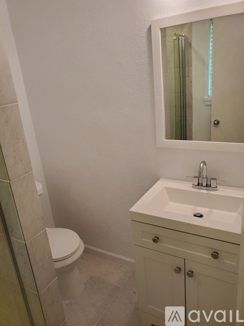 A bathroom with a toilet, sink, and mirror.