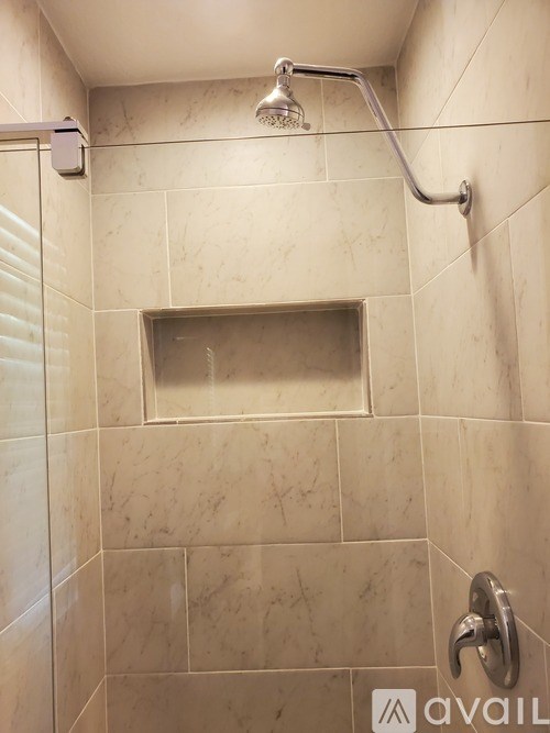 A shower area with a tiled wall and a rectangular shower head.