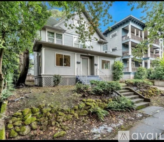 A house with a front yard and a staircase leading to a balcony.