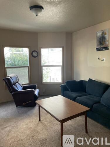 A living room with a blue couch, a brown coffee table, and a window.