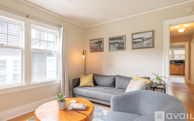 A living room with a grey couch, a wooden table, and a grey armchair.