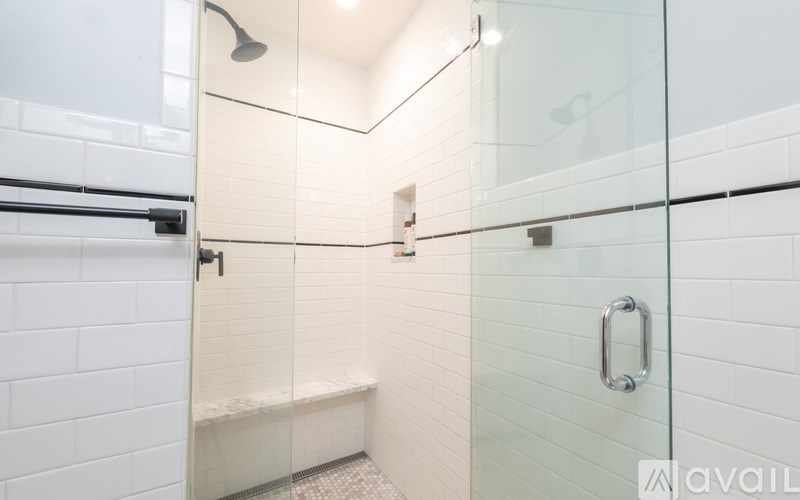 A white tiled bathroom with a glass shower door.