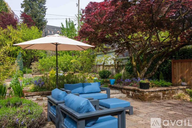 A patio with a blue couch and a white umbrella.