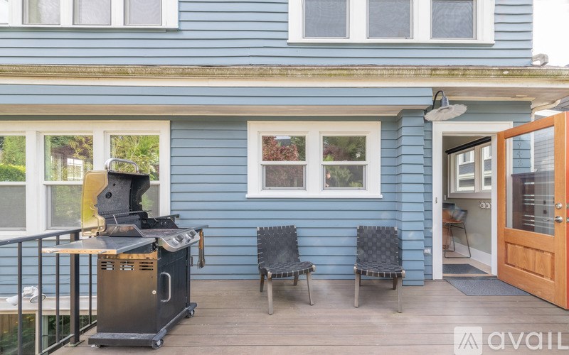 A blue house with a grill on the deck.