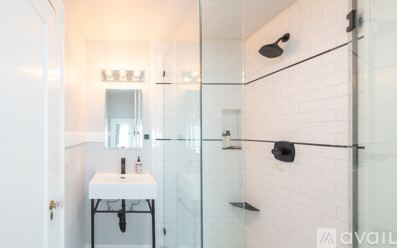 A bathroom with a white tile wall and a glass shower door.