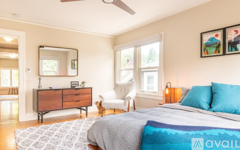 A bedroom with a bed, a chair, a dresser, and a mirror.