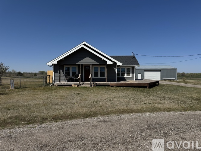 A house with a grey roof and a white garage door is for sale.