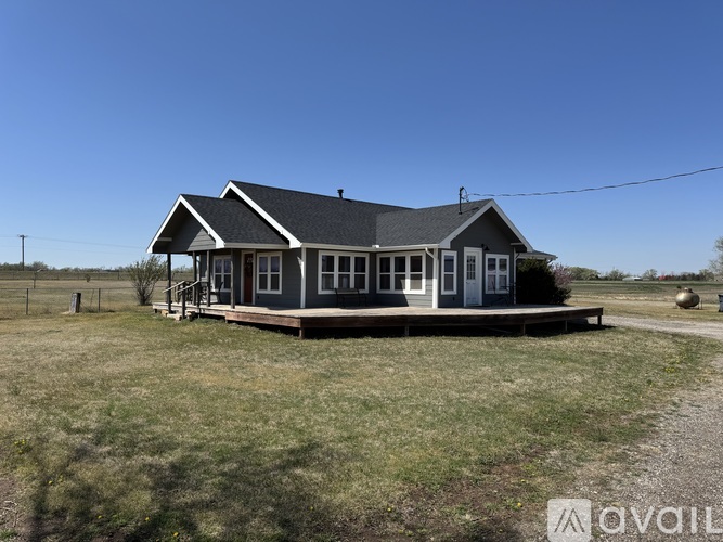 A small house with a porch is situated in a grassy field.
