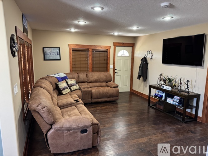 A living room with a brown couch and a flat screen TV mounted on the wall.