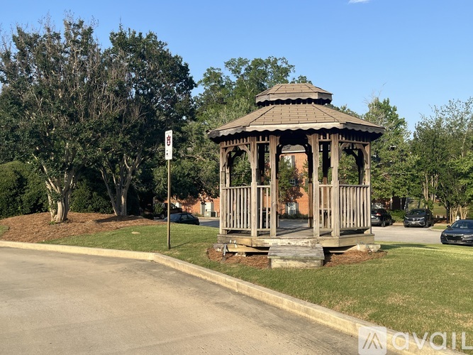A gazebo is situated in a grassy area next to a road.