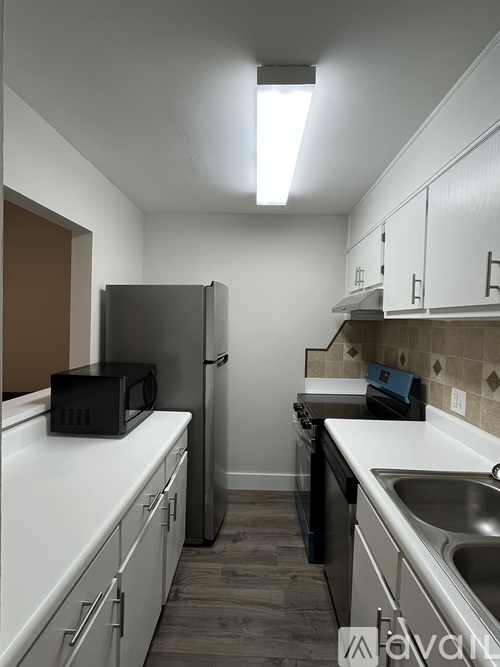 A kitchen with white countertops and a black fridge.