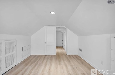 A spacious room with wooden floors and white walls.