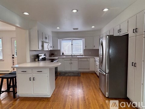 A kitchen with white cabinets and a black refrigerator.