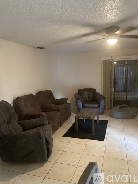 A living room with a brown couch and a black rug.