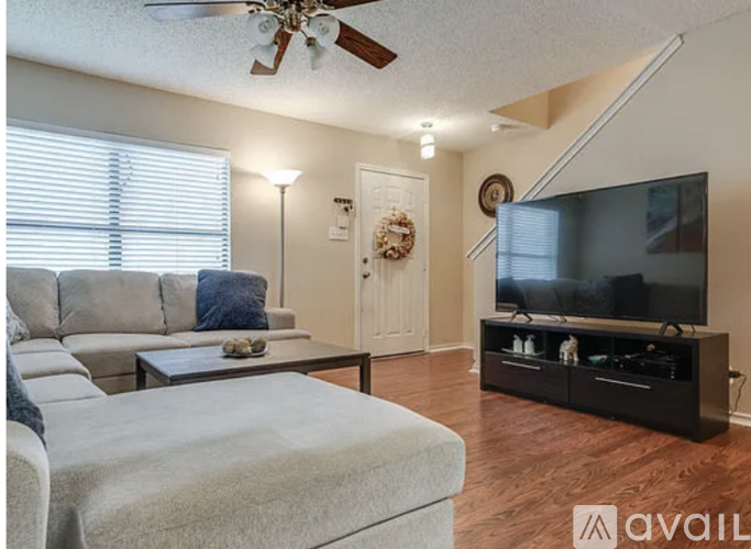 A living room with a grey sofa and a wooden floor.