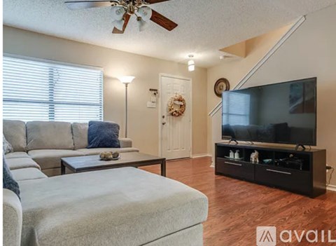 A living room with a grey sofa and a wooden floor.