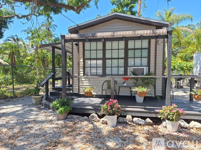 A small house with a porch and a balcony surrounded by plants.