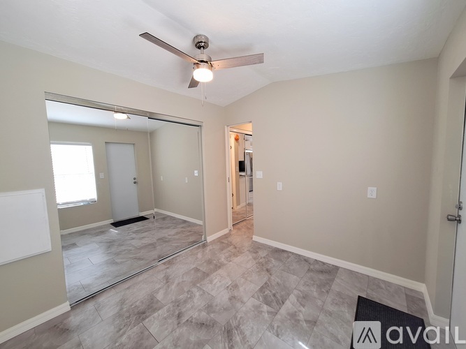 A spacious room with a ceiling fan and a large mirror on the wall.