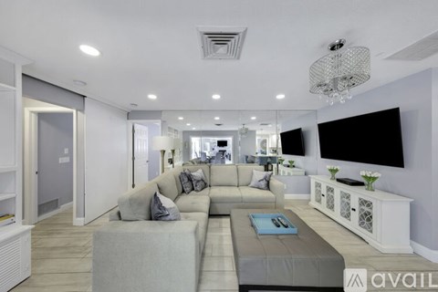 A modern living room with a grey sofa and a chandelier.