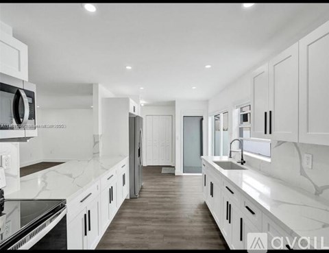 A modern kitchen with white cabinets and a marble countertop.