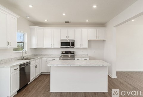 A kitchen with white cabinets and a marble countertop.
