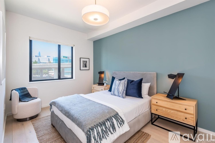 A bedroom with a large bed, a chair, and a window overlooking a cityscape.