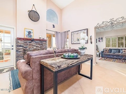 A living room with a brown couch and a stone fireplace.
