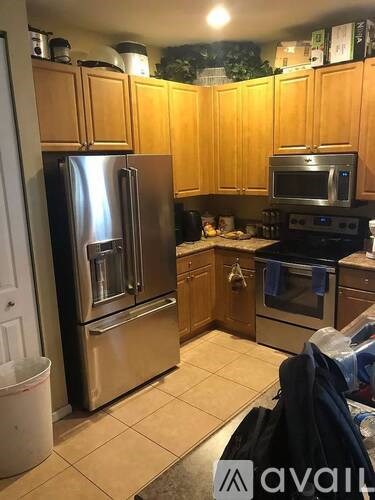 A kitchen with wooden cabinets and a stainless steel refrigerator.