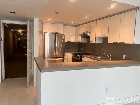A modern kitchen with a stainless steel refrigerator and a white countertop.
