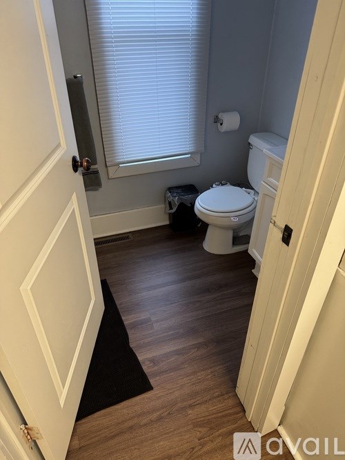 A bathroom with a toilet, sink, and window.