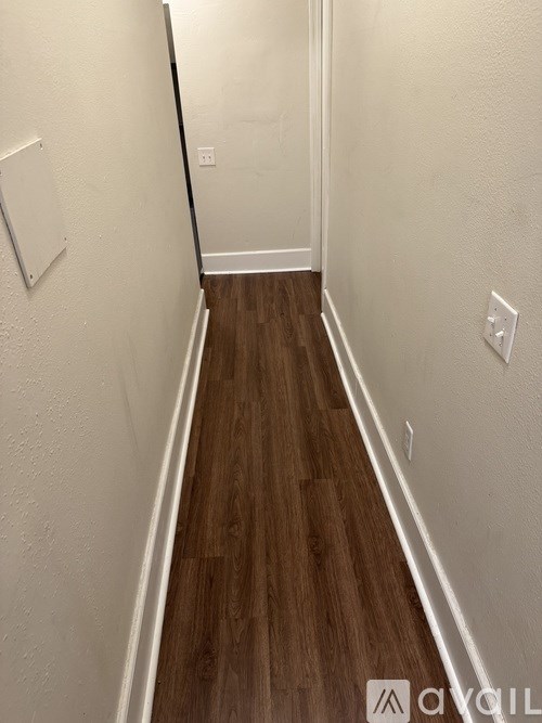 A hallway with wood flooring and white walls.
