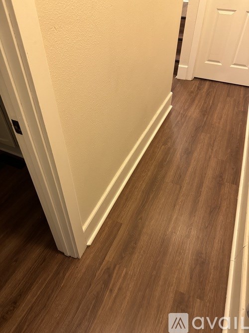 A hallway with a wooden floor and white walls.