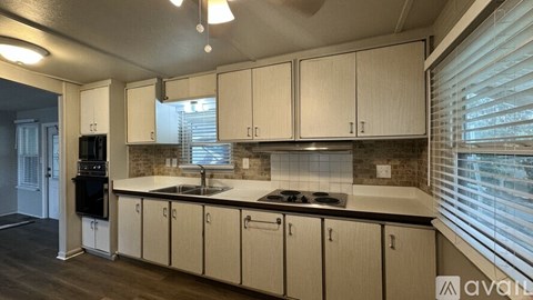 A kitchen with beige cabinets and a black stove top oven.