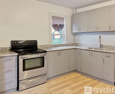 A kitchen with a stove and oven, cabinets, and a window.