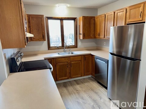 A kitchen with wooden cabinets and a stainless steel refrigerator.