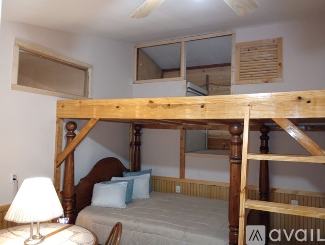 A bedroom with a wooden bunk bed and a single bed underneath.