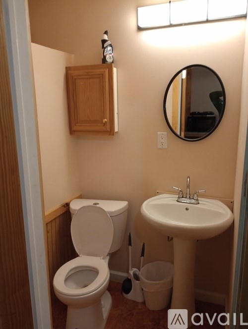 A bathroom with a toilet, sink, and mirror.