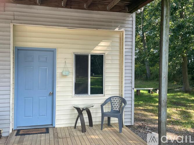 A blue door is on the left of a white house.