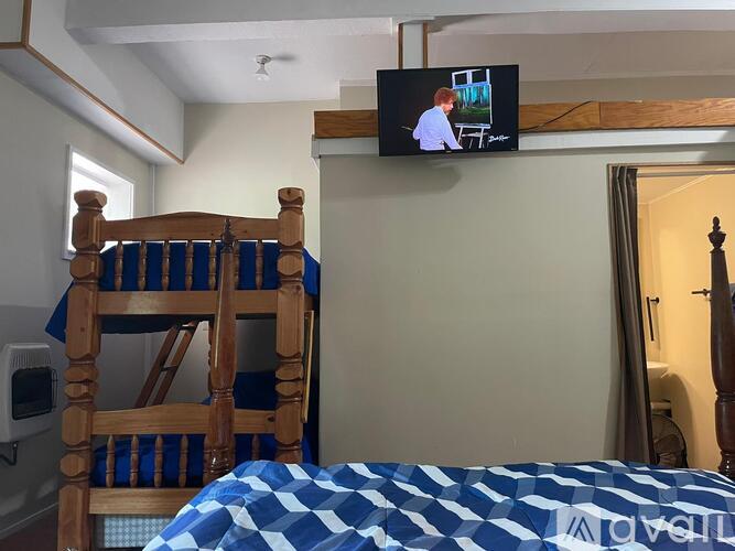 A bedroom with a bed, a chair, and a television mounted on the wall.