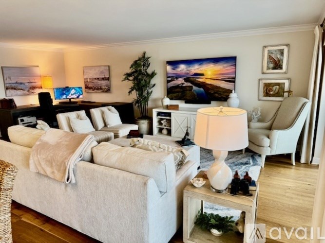 A well-lit bedroom with a large bed and a painting on the wall.