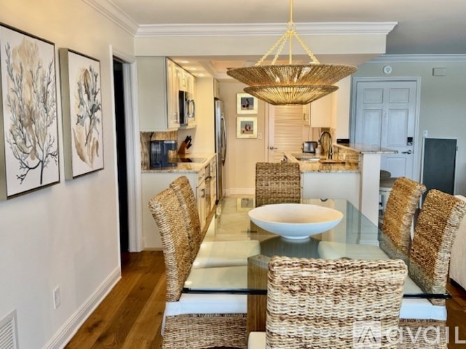 A modern dining room with a glass table and wicker chairs.