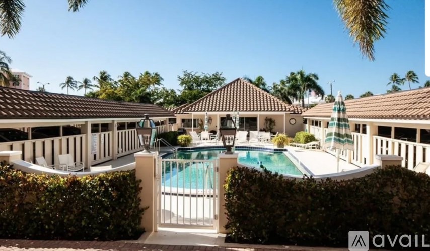 A pool surrounded by a white fence and green bushes.
